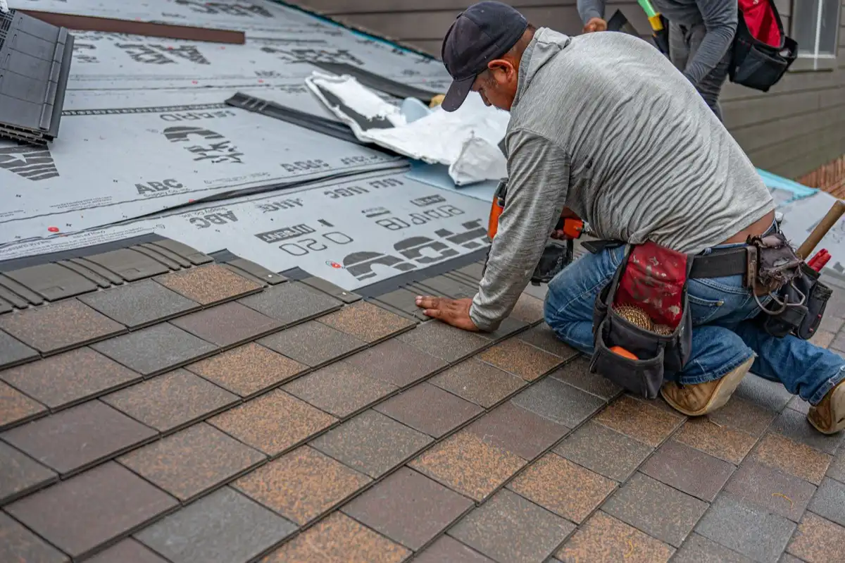 Roofer nailing the cap course along a ridge on a home in Roseville, CA